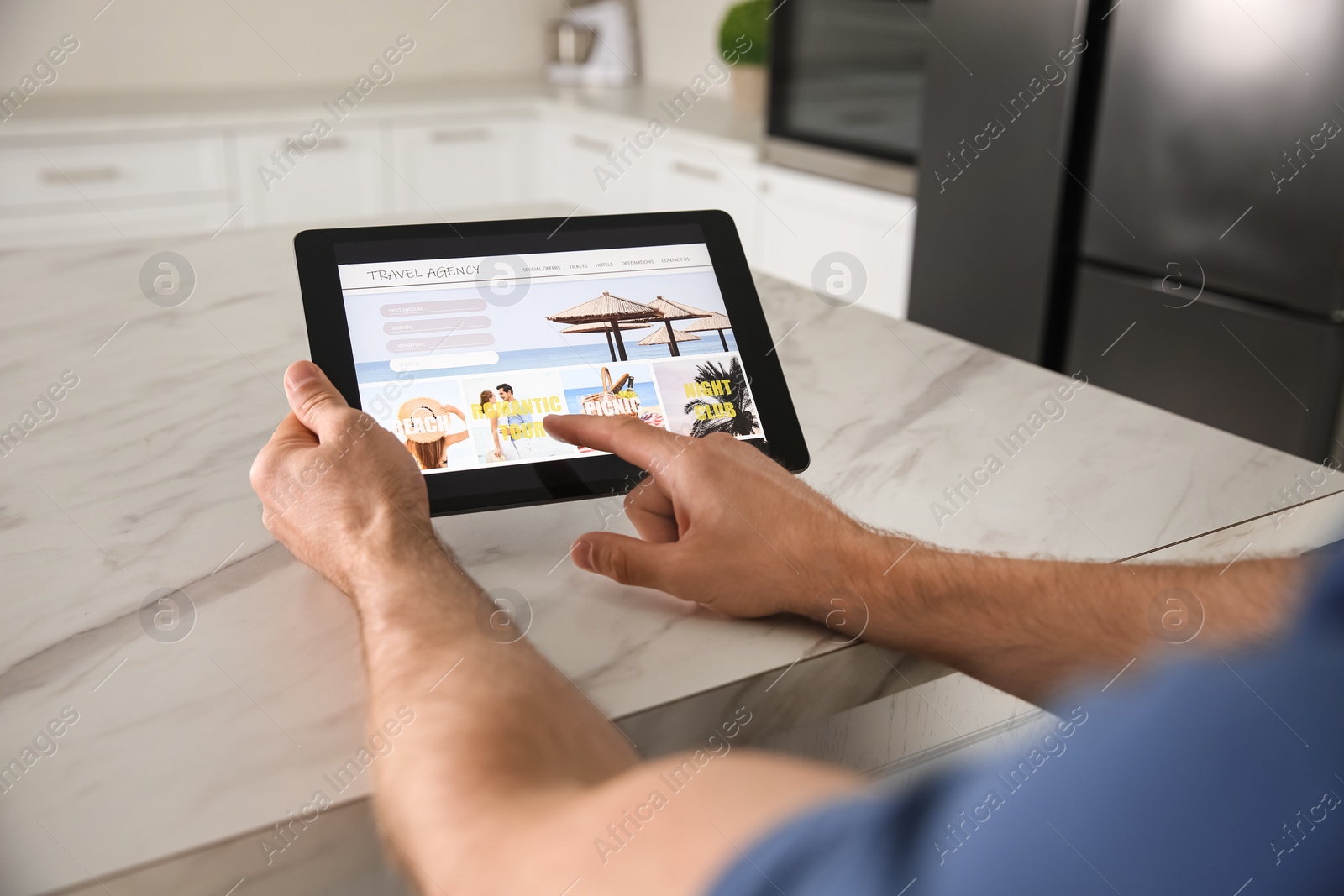 Photo of Man booking tickets online on tablet at table, closeup. Travel agency concept