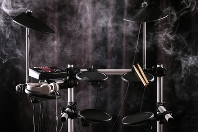 Photo of Modern electronic drum kit and smoke on dark background. Musical instrument