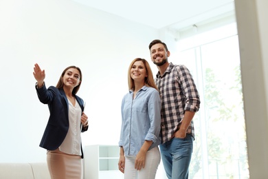 Photo of Female real estate agent showing new house to couple, indoors