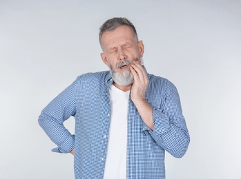 Photo of Man suffering from toothache on light background