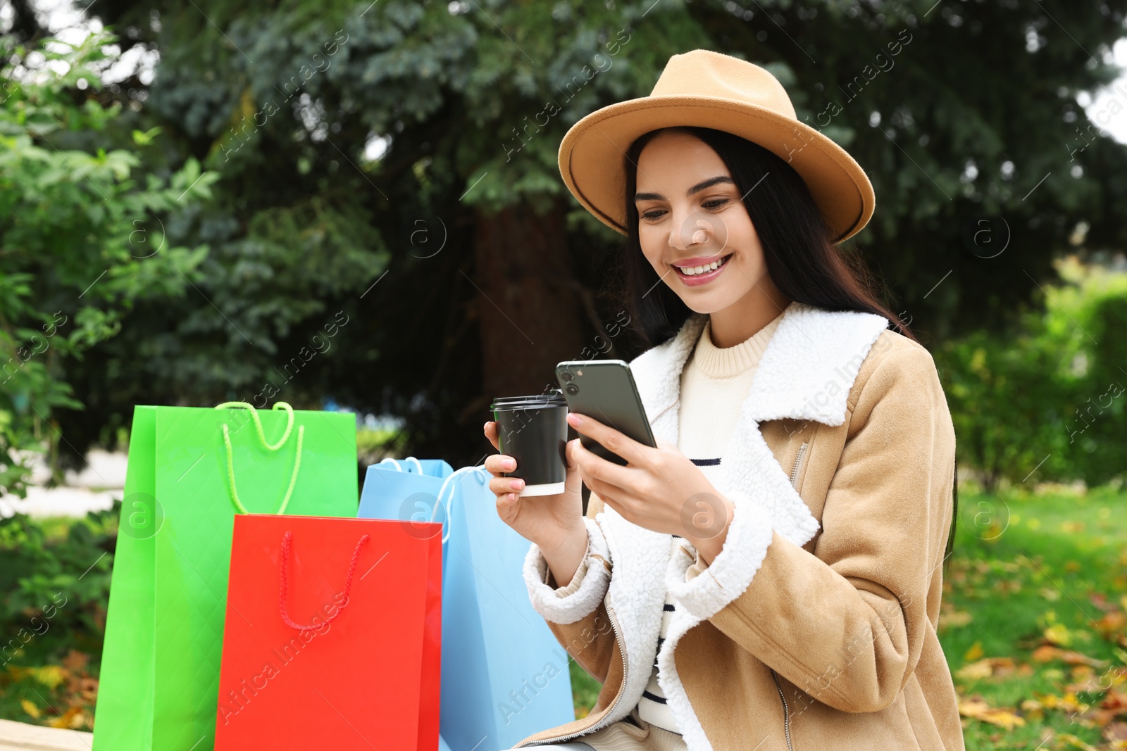 Photo of Special Promotion. Happy young woman with smartphone and cup of drink in park