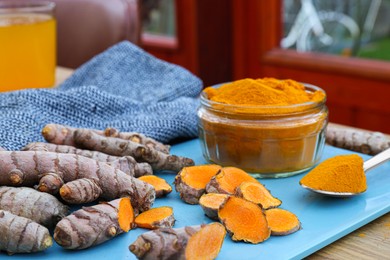 Photo of Tray with glass jar of turmeric powder and roots on table
