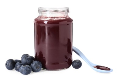Photo of Jar of healthy baby food, fresh blueberries and spoon isolated on white
