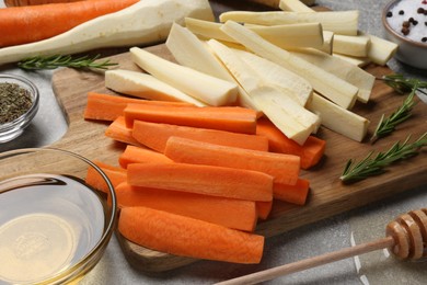 Raw parsnips, carrots and other products on light grey table