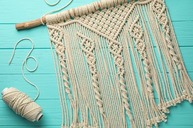 Photo of Stylish beige macrame and cord on turquoise wooden table, top view
