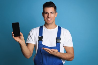 Photo of Repairman with modern smartphone on blue background