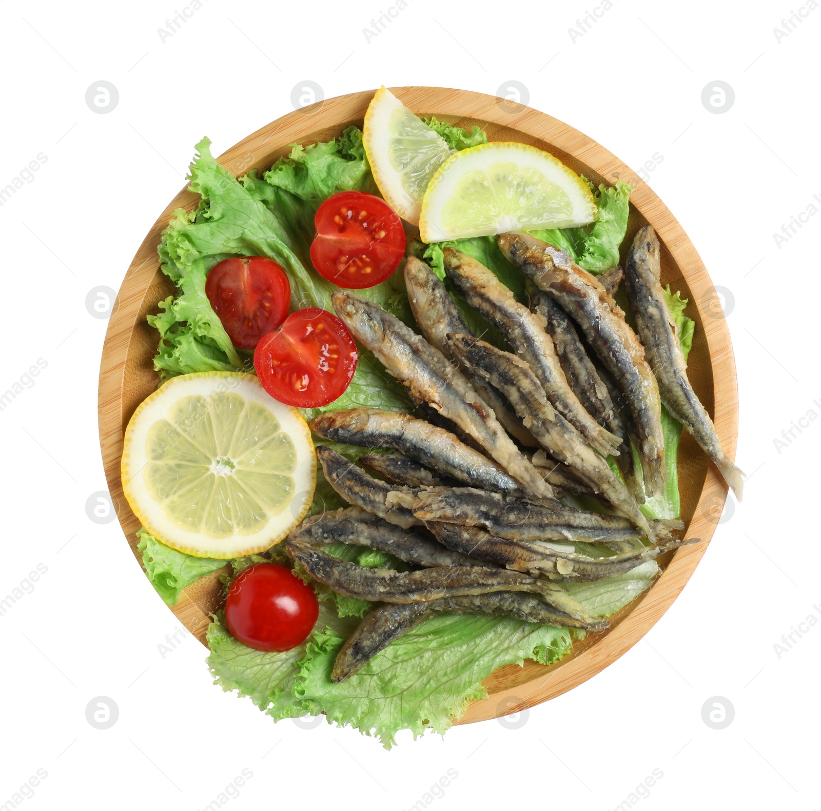 Photo of Wooden plate with delicious fried anchovies, lemon slices, tomatoes and lettuce leaves on white background, top view