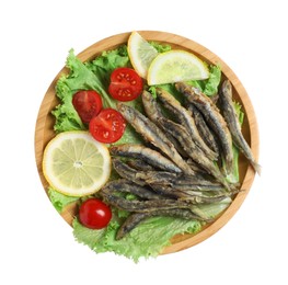 Wooden plate with delicious fried anchovies, lemon slices, tomatoes and lettuce leaves on white background, top view