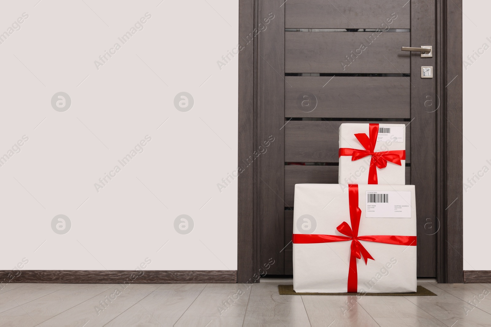 Photo of Christmas gift boxes on floor near door, space for text. Sending present by mail