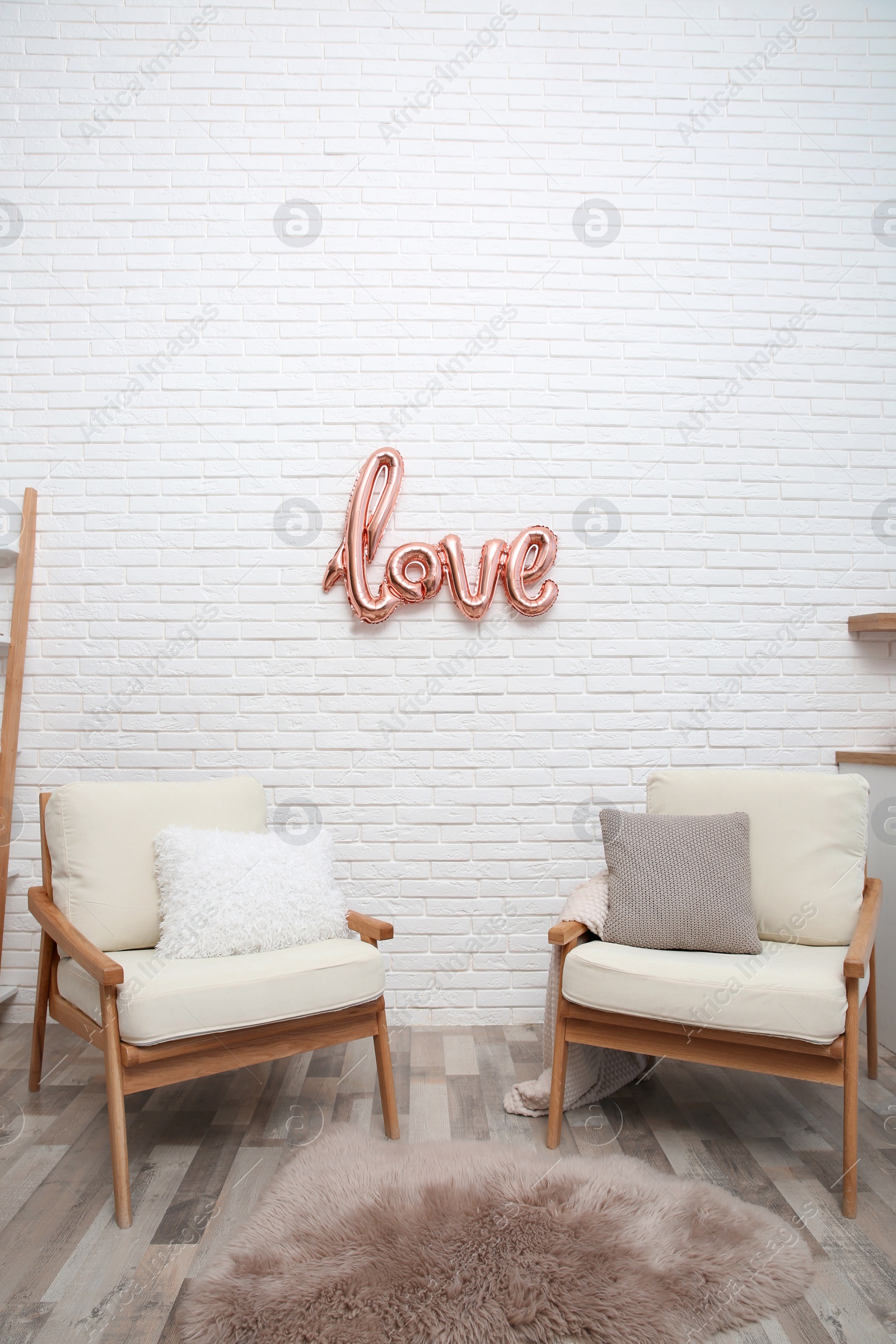 Photo of Cozy room interior with armchairs and balloon in shape of word Love. Valentine Day celebration