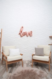 Cozy room interior with armchairs and balloon in shape of word Love. Valentine Day celebration