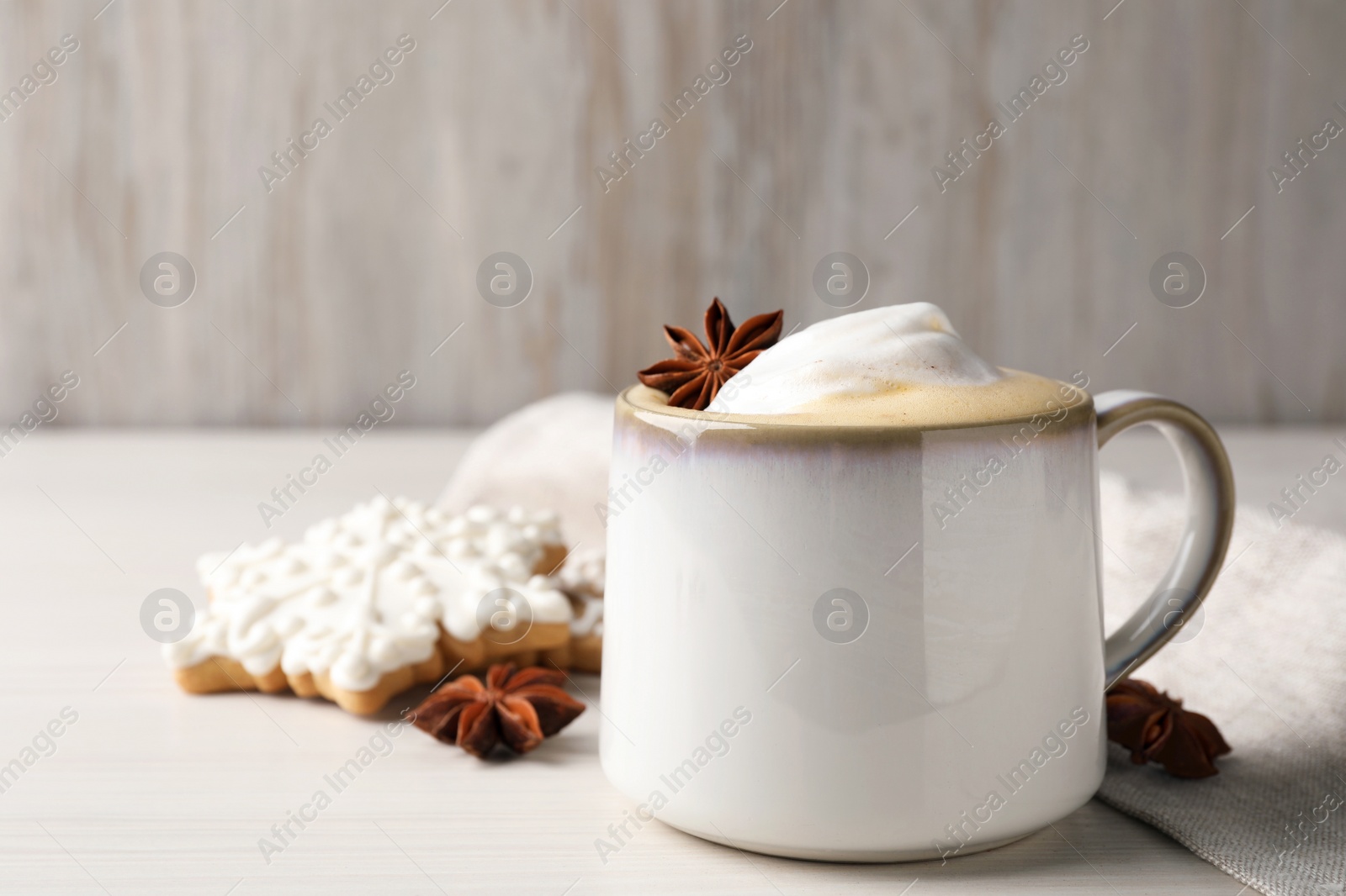 Photo of Cup of delicious eggnog with anise star on wooden table, space for text