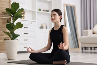 Beautiful girl meditating on yoga mat at home