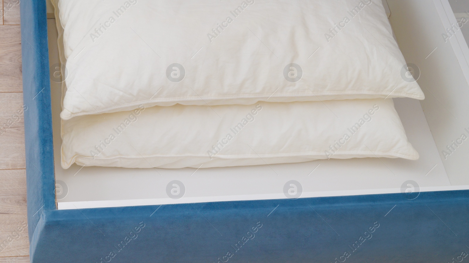 Photo of Storage drawer under bed with white pillows indoors, closeup