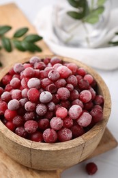 Photo of Frozen red cranberries in bowl on table, closeup