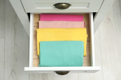 Photo of Chest of drawers with different folded clothes indoors, top view