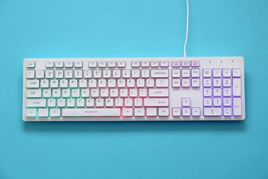 Photo of Modern RGB keyboard on turquoise background, top view