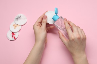 Woman using makeup remover, closeup. Dirty cotton pads on pink background, top view