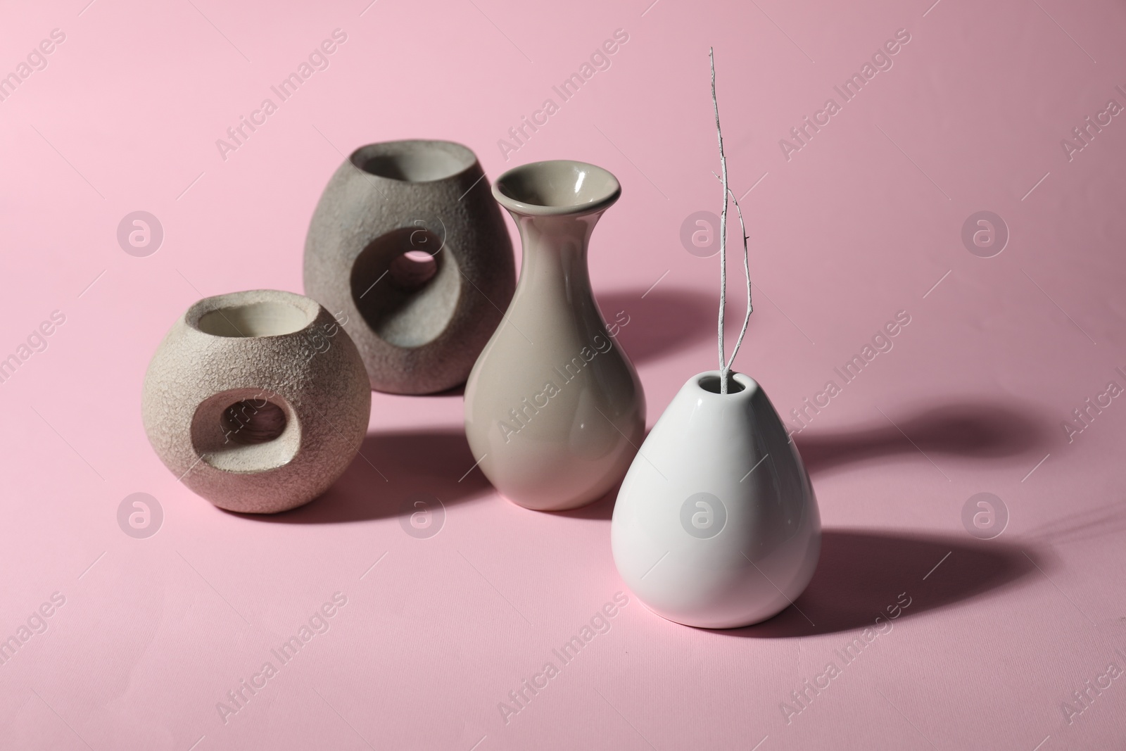 Photo of Different stylish vases and branch on pink background