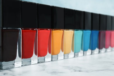 Photo of Bright nail polishes on table against color background, closeup