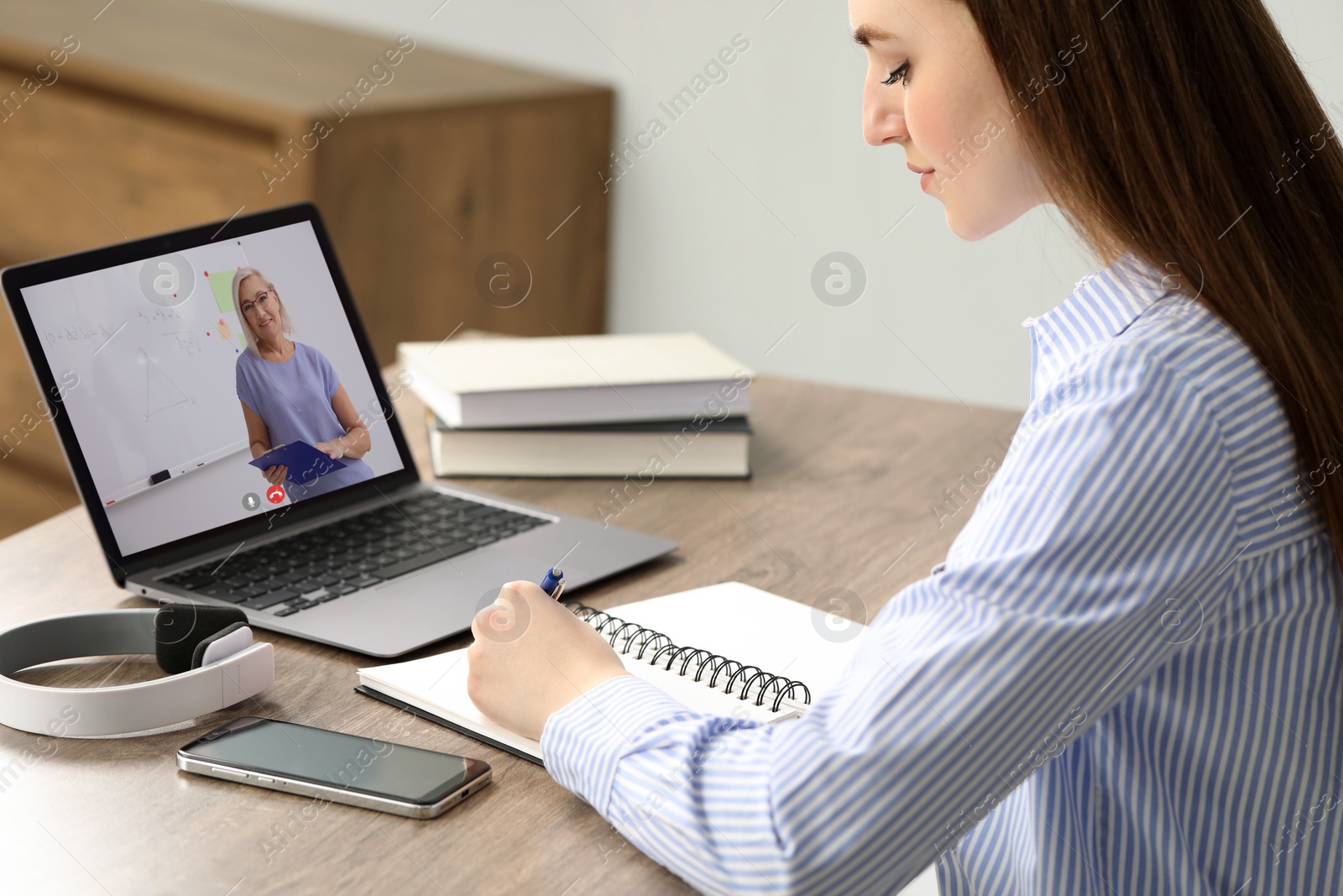 Image of E-learning. Young woman having online lesson with teacher via laptop at home