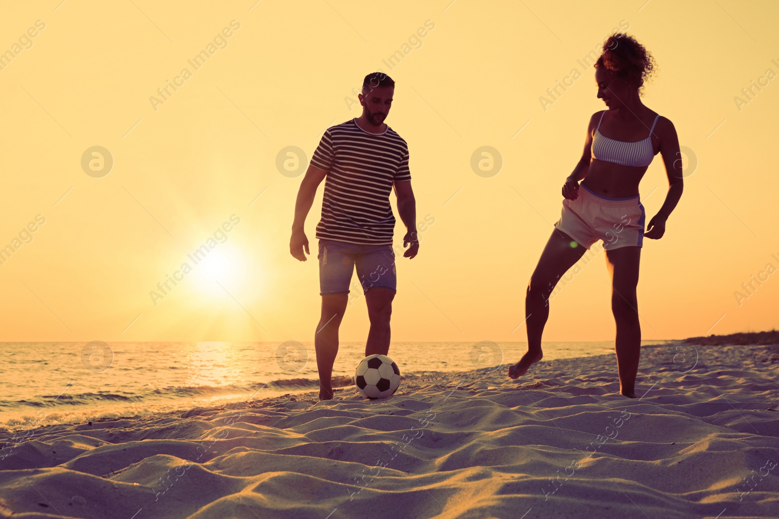 Photo of Friends playing football on beach at sunset