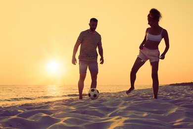 Photo of Friends playing football on beach at sunset