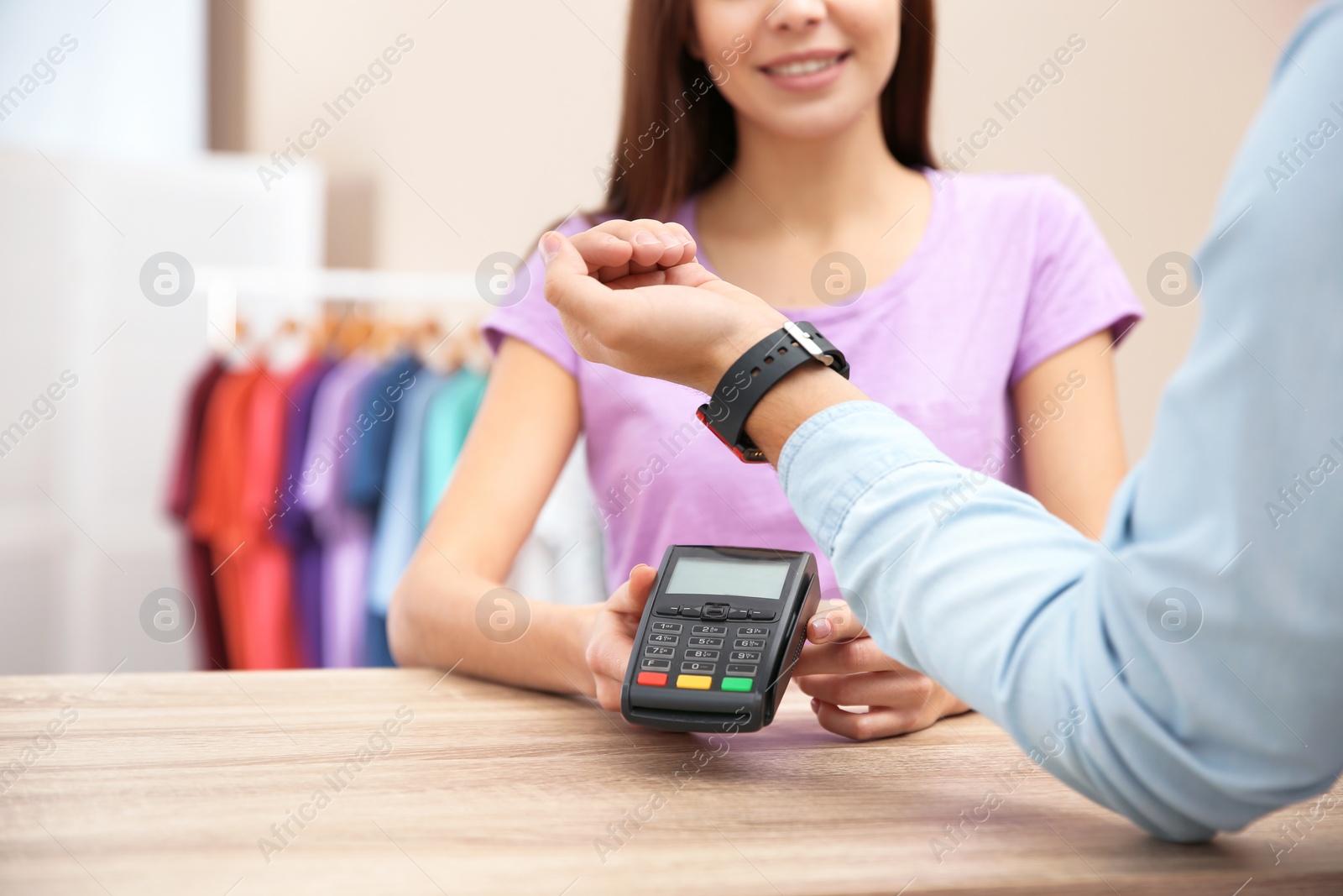 Photo of Man using terminal for contactless payment with smart watch in shop, closeup