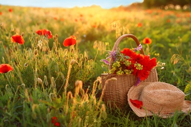 Photo of Basket of wildflowers with straw hat in sunlit poppy field