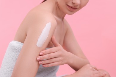 Photo of Woman with smear of body cream on her shoulder against pink background, closeup