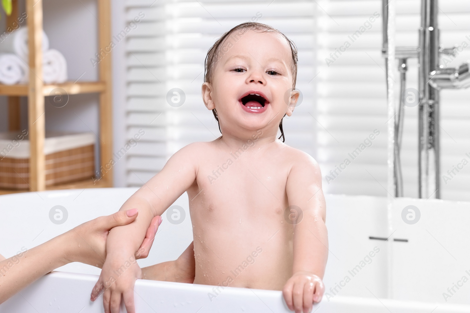 Photo of Mother bathing her cute little baby in tub at home