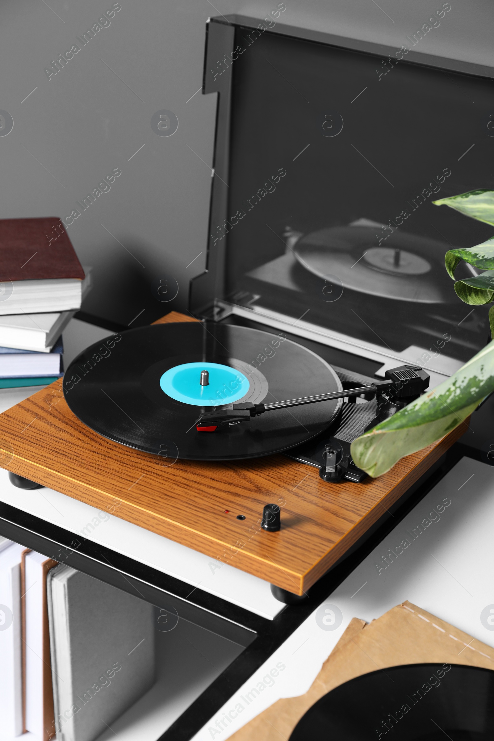 Photo of Stylish turntable with vinyl disc near grey wall in room