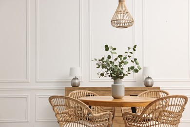 Photo of Dining room interior with comfortable furniture and eucalyptus branches. Space for text