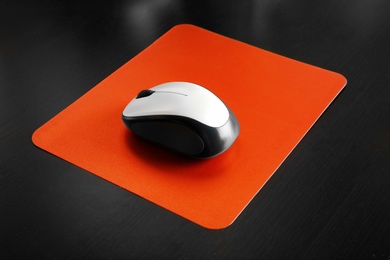 Photo of Blank pad and wireless computer mouse on black background