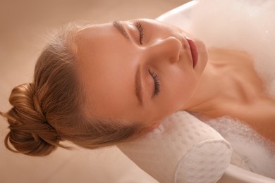 Young woman using pillow while enjoying bubble bath indoors, closeup