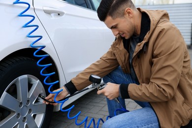 Photo of Handsome man inflating tire at car service
