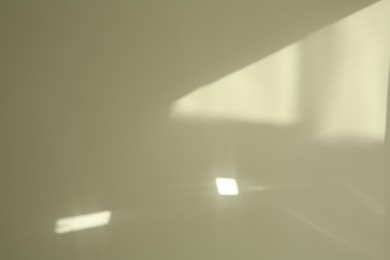 Photo of Light and shadow from window on beige wall indoors