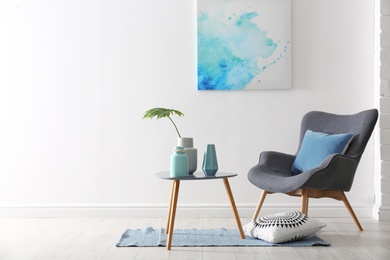 Photo of Living room interior with vases on table and armchair near white wall. Space for text