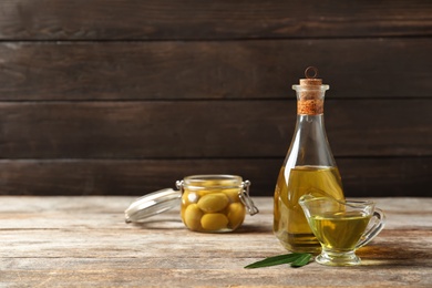 Photo of Beautiful composition with oil and ripe olives on wooden table