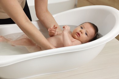 Photo of Mother bathing her little baby in bathtub, closeup