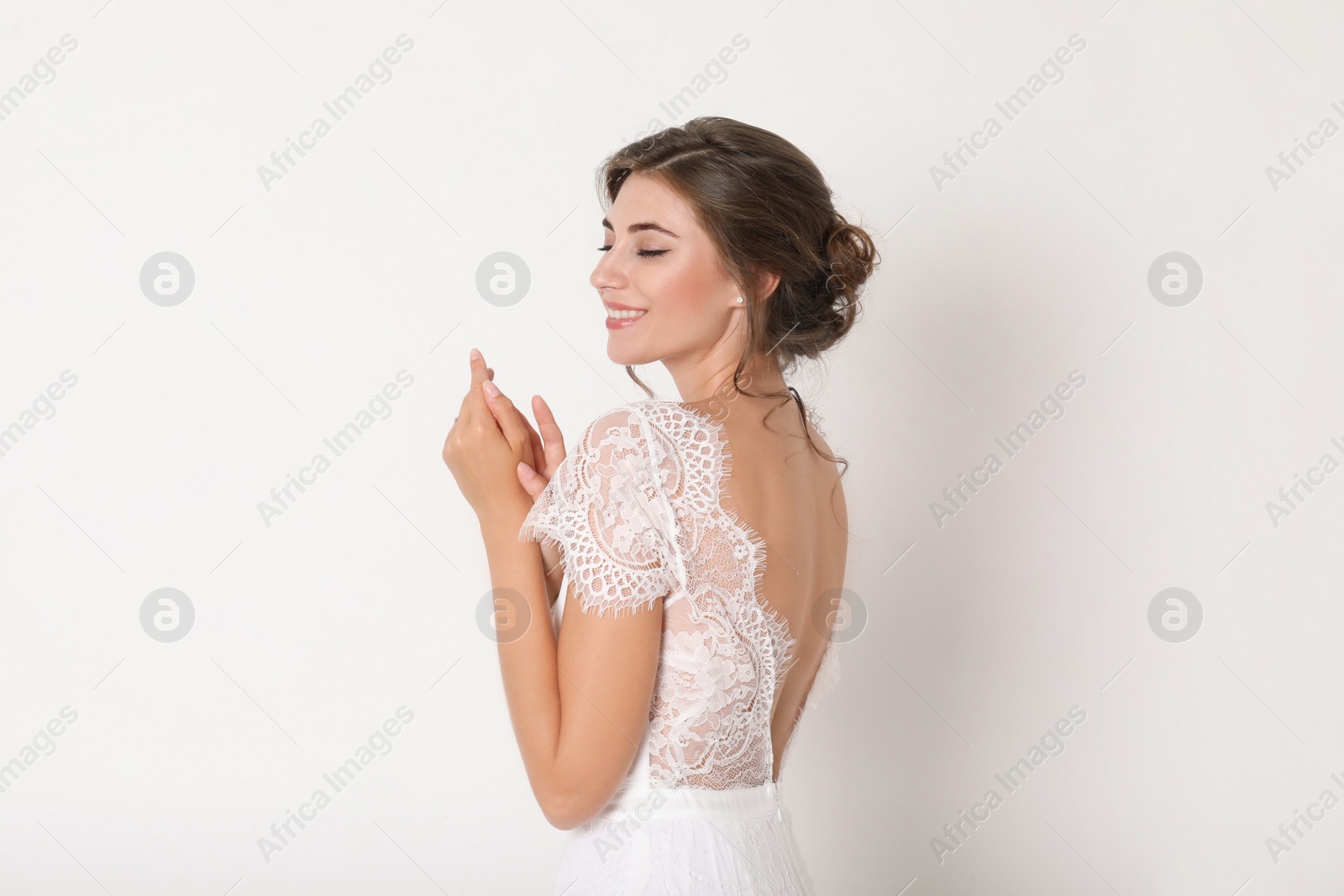 Photo of Young bride wearing beautiful wedding dress on light background