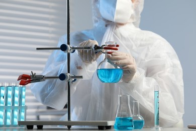Scientist working with flask of light blue liquid in laboratory, closeup