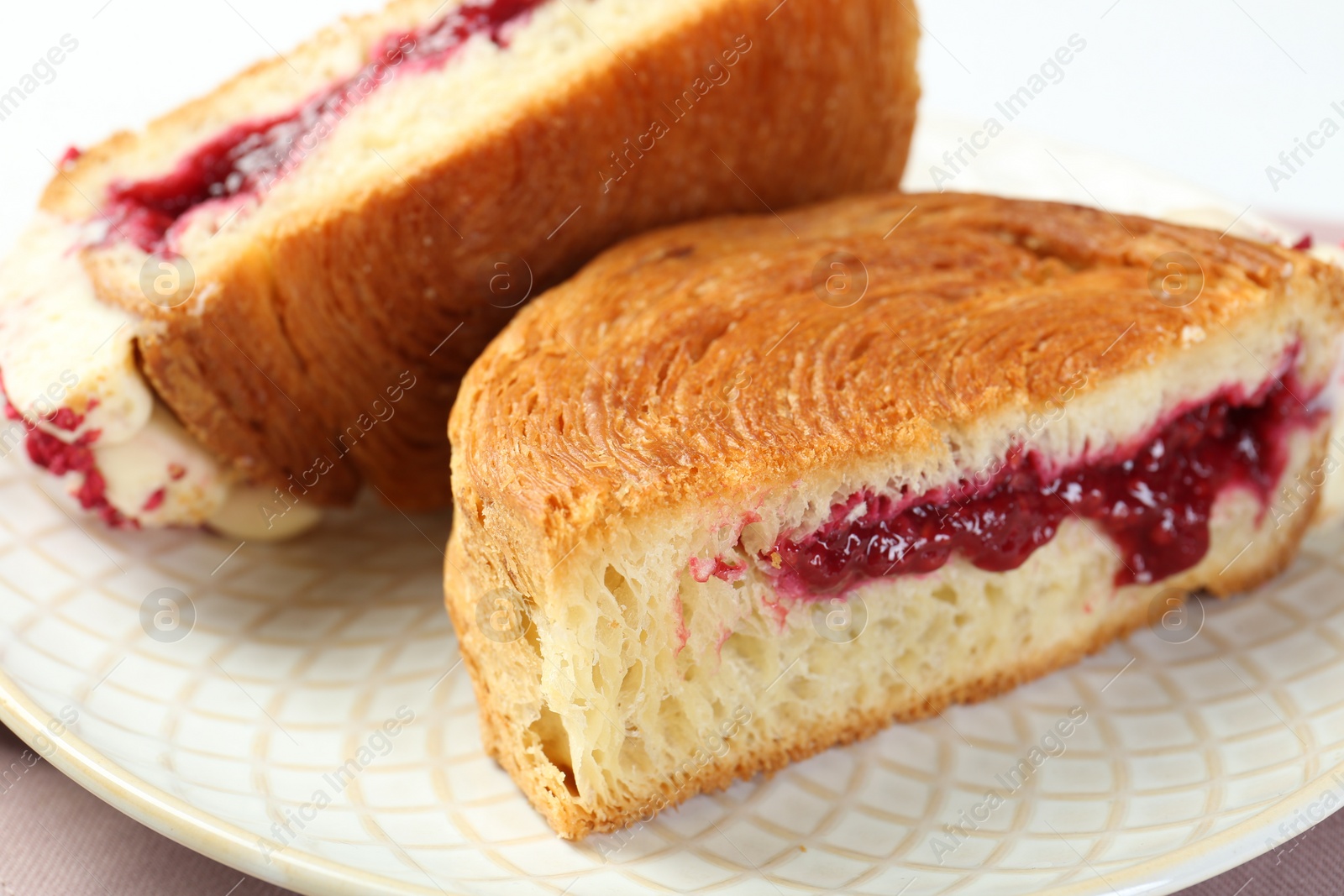 Photo of Round croissant with jam on table, closeup. Tasty puff pastry