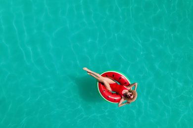 Young happy woman with inflatable ring in swimming pool, top view. Summer vacation