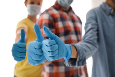 Photo of Group of people in blue medical gloves showing thumbs up on blurred background, closeup