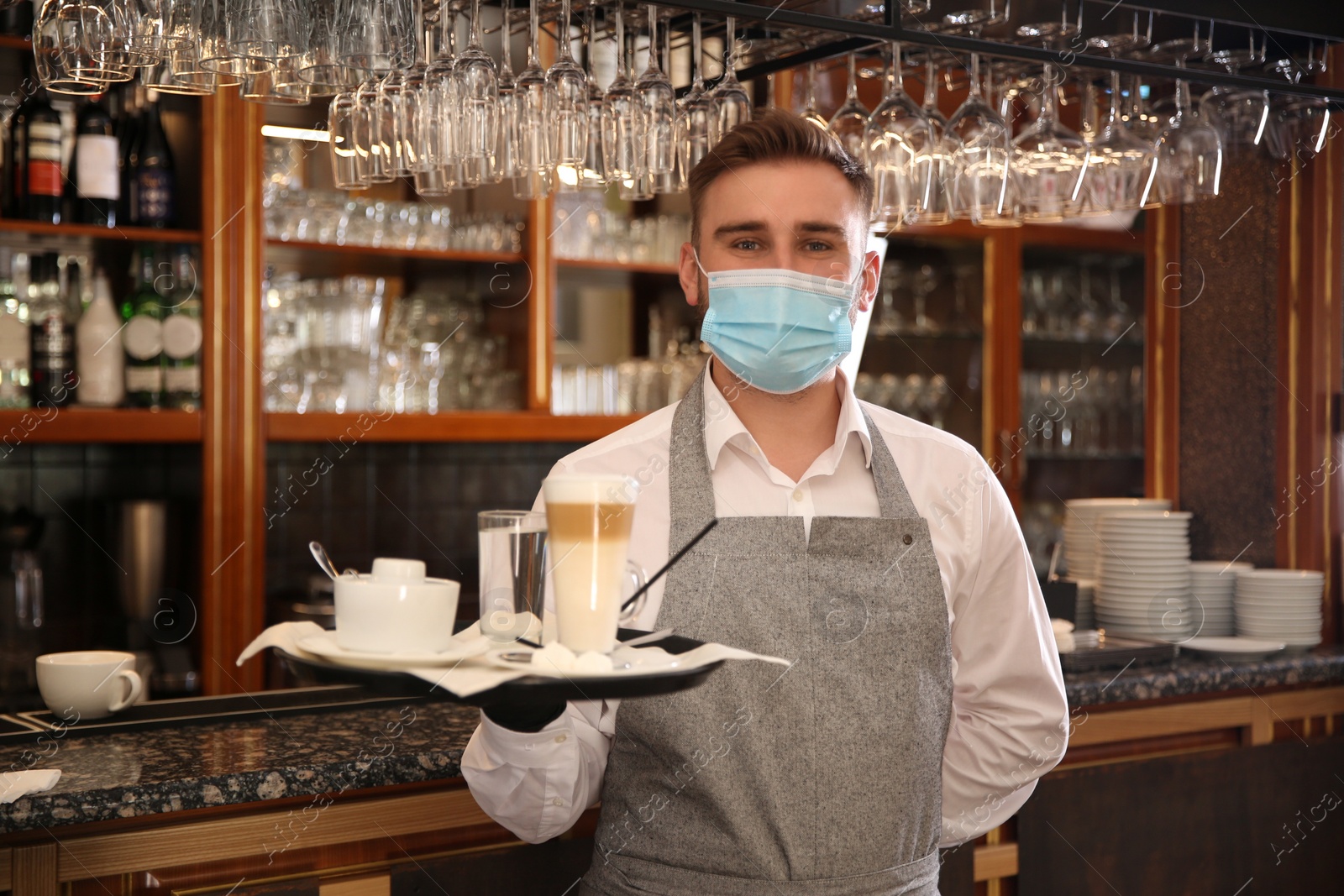 Photo of Waiter holding tray with beverages in restaurant. Catering during coronavirus quarantine