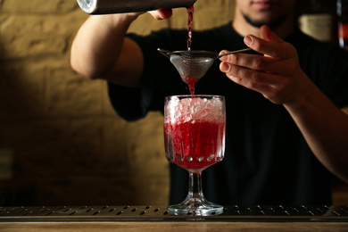 Bartender preparing fresh alcoholic cocktail at bar counter, closeup