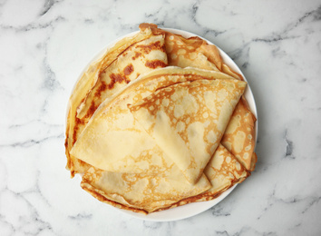 Photo of Stack of fresh thin pancakes on white marble table, top view