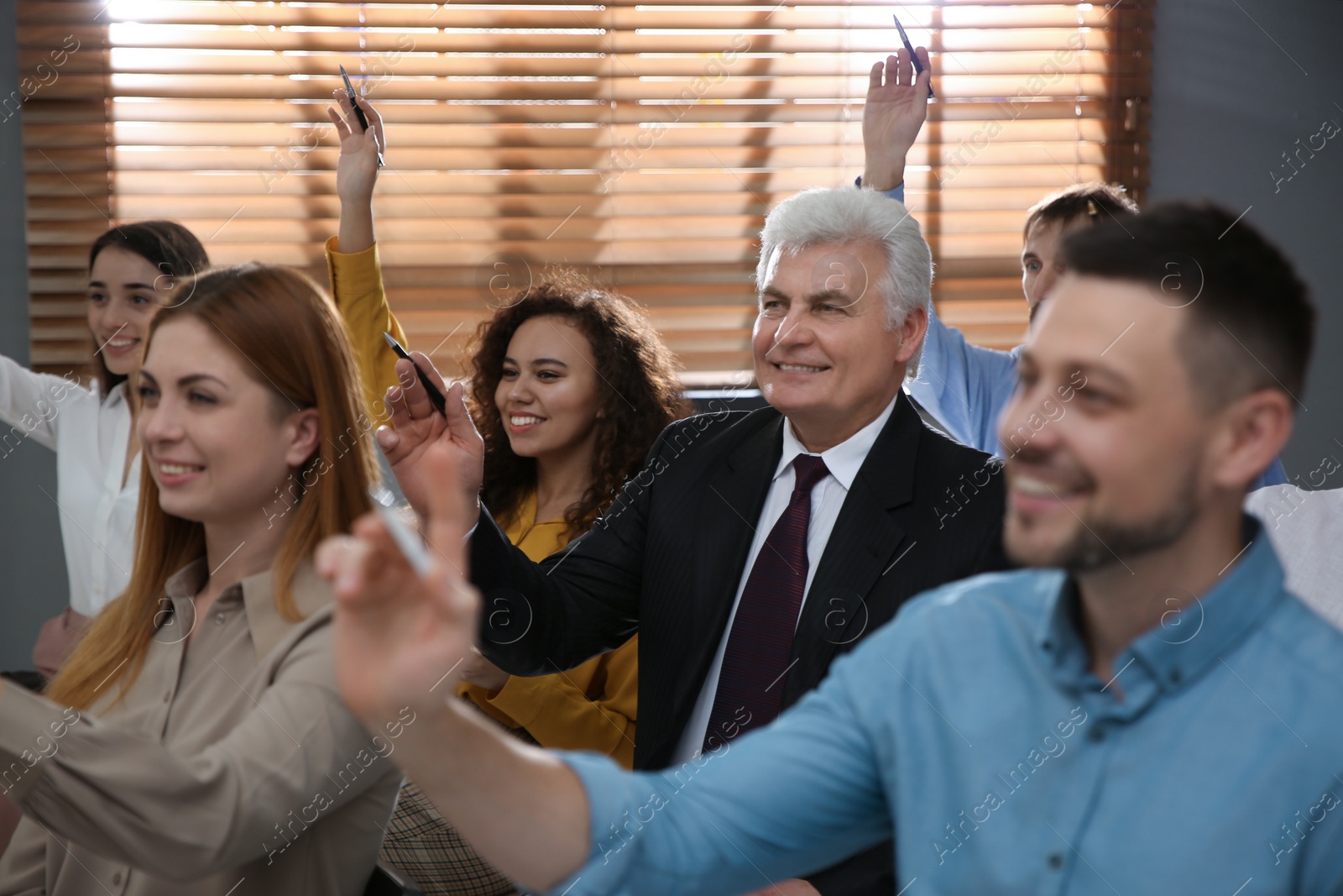 Photo of People raising hands to ask questions at seminar in office