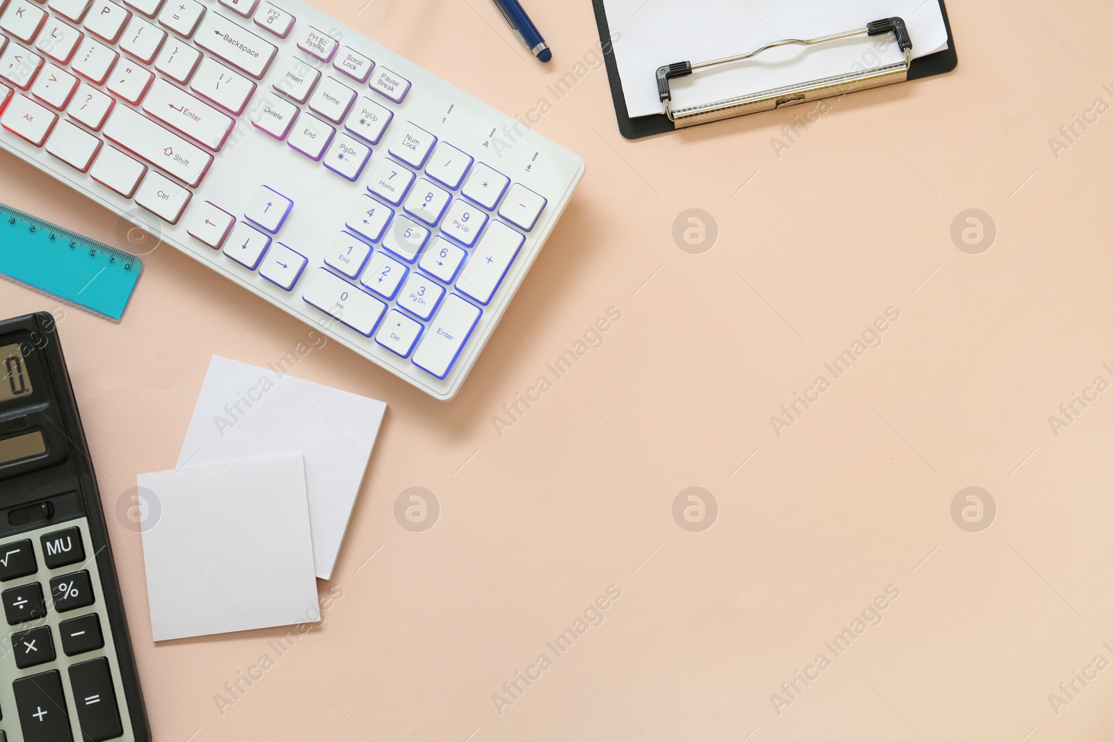 Photo of Modern keyboard with RGB lighting and stationery on light pink background, flat lay. Space for text